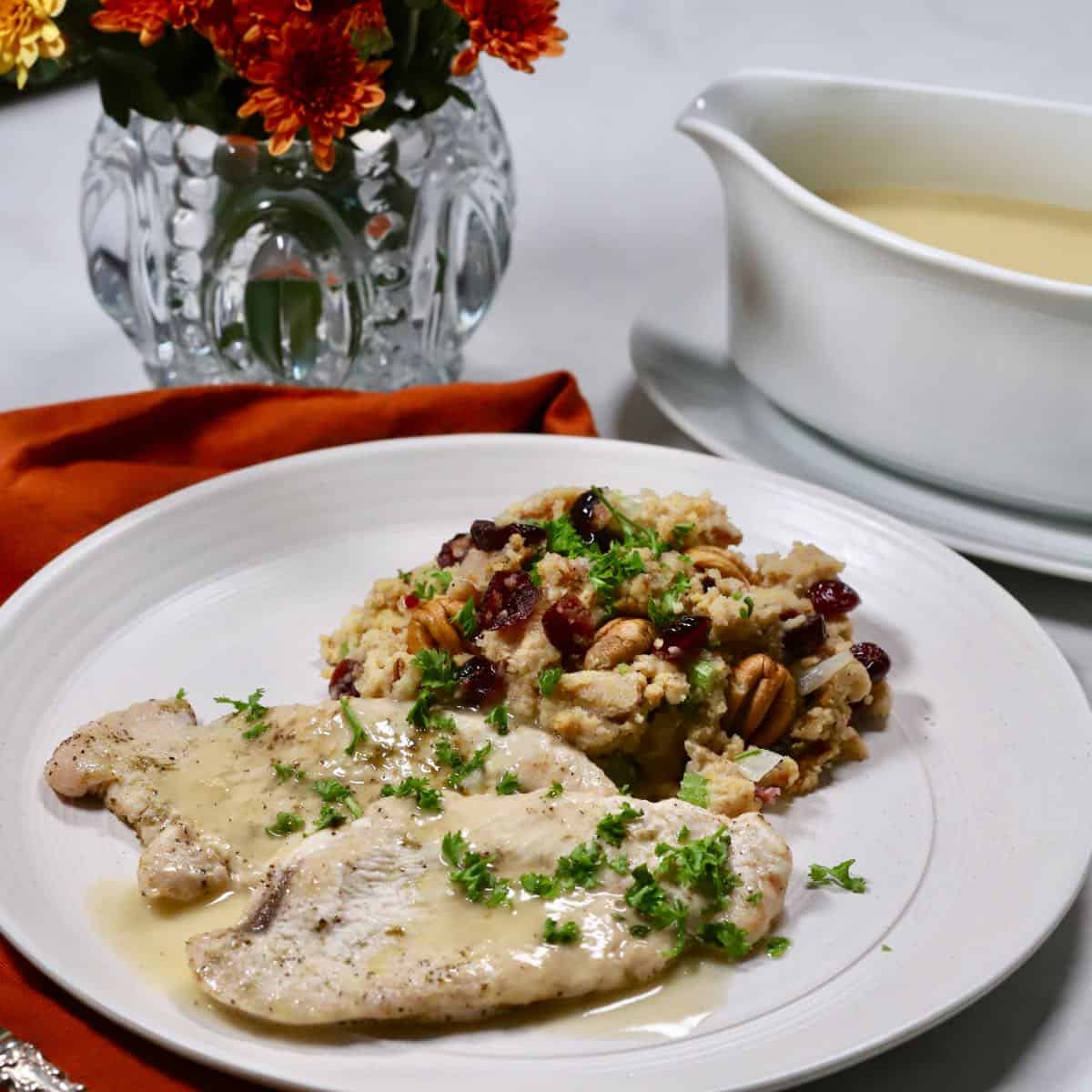 Turkey cutlets topped with gravy and a serving of cornbread dressing on a plate.