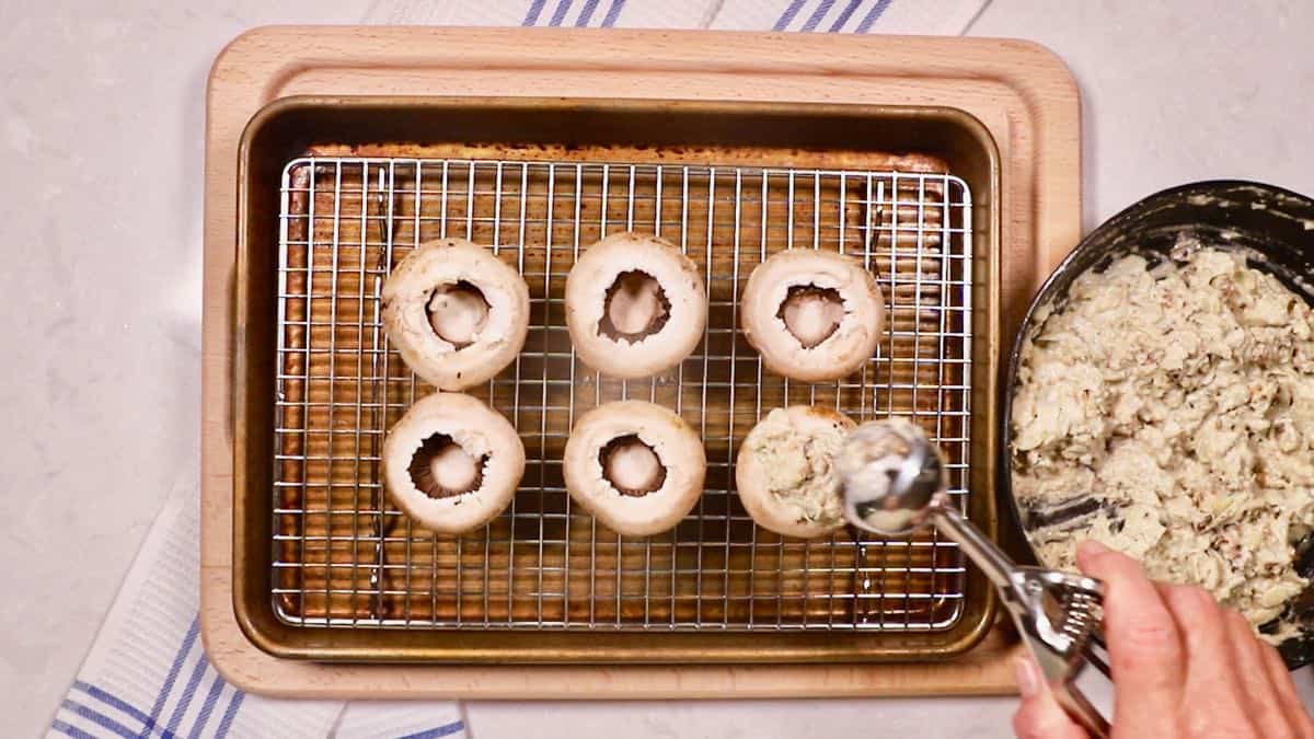 Stuffing fresh mushroom caps with artichoke stuffing. 