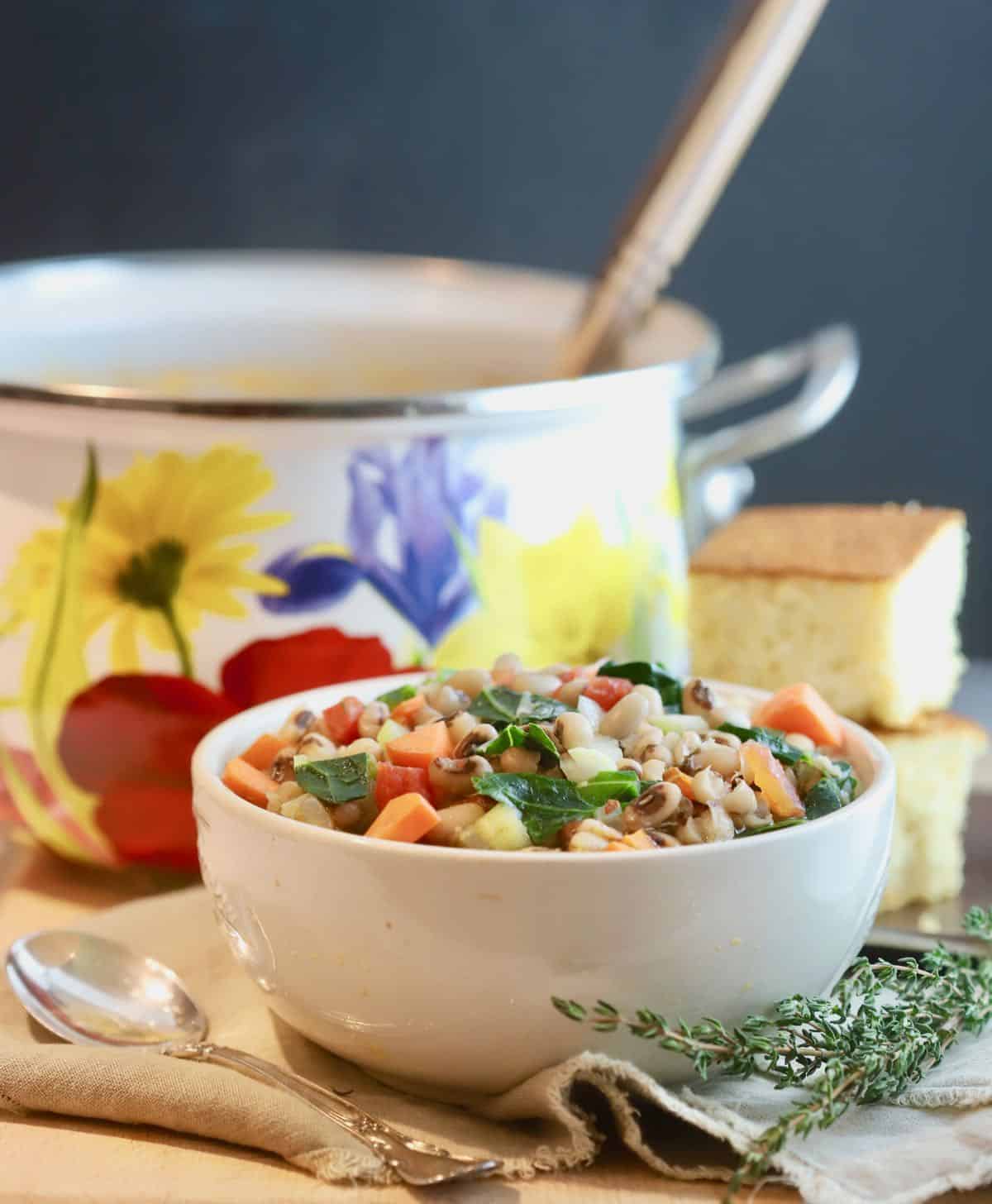 A Dutch oven full of black-eyed pea soup and a bowl of soup. 