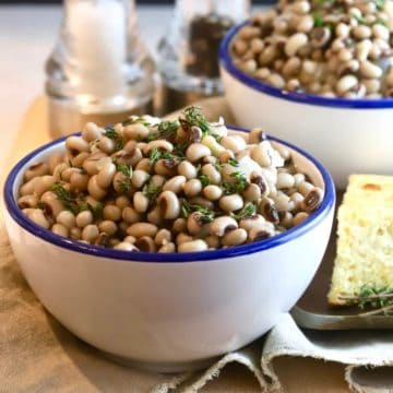 Two bowls of black-eyed-peas and a piece of cornbread.