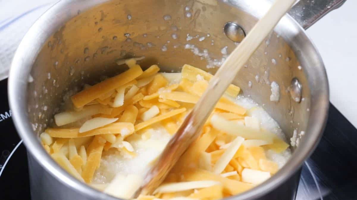 Mixing cheese in to a pan of grits cooking. 