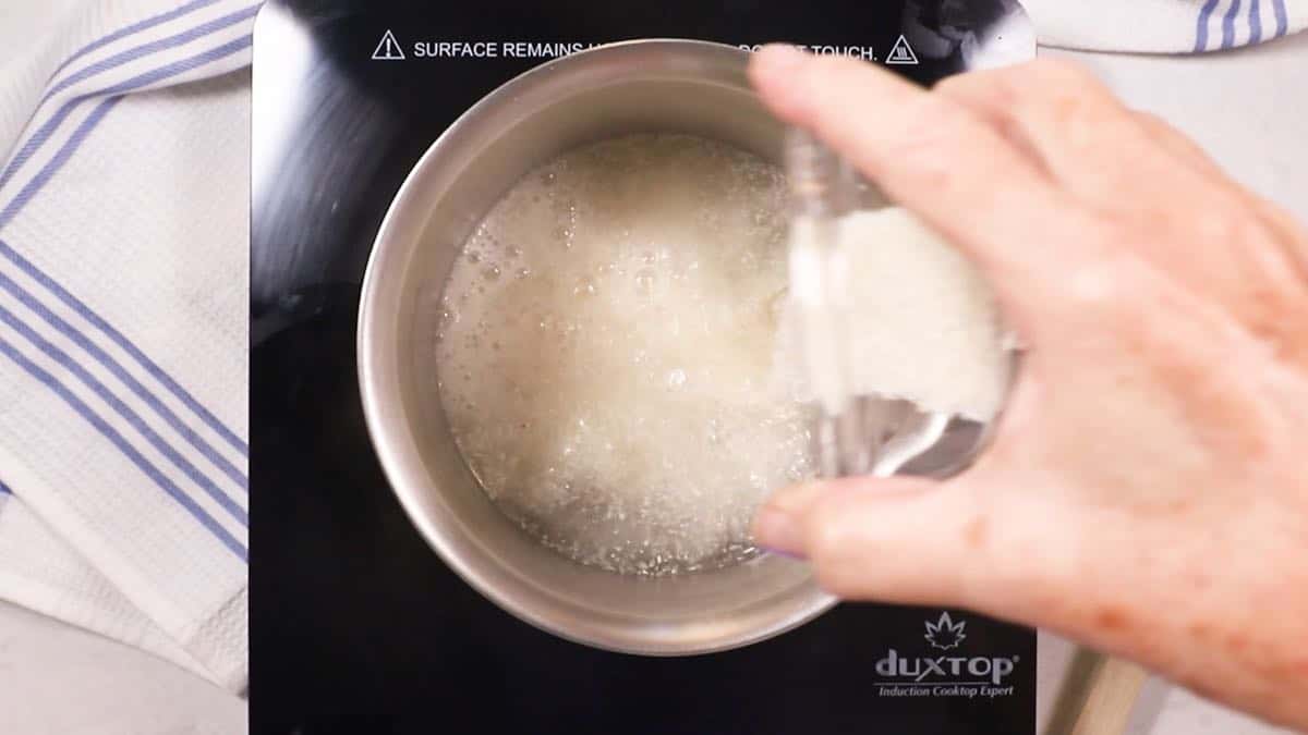 Adding grits to boiling water in a saucepan. 