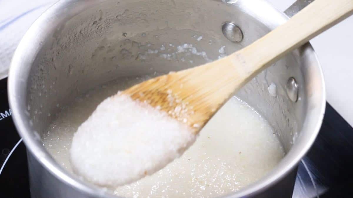 Using a wooden spoon to stir grits cooking. 