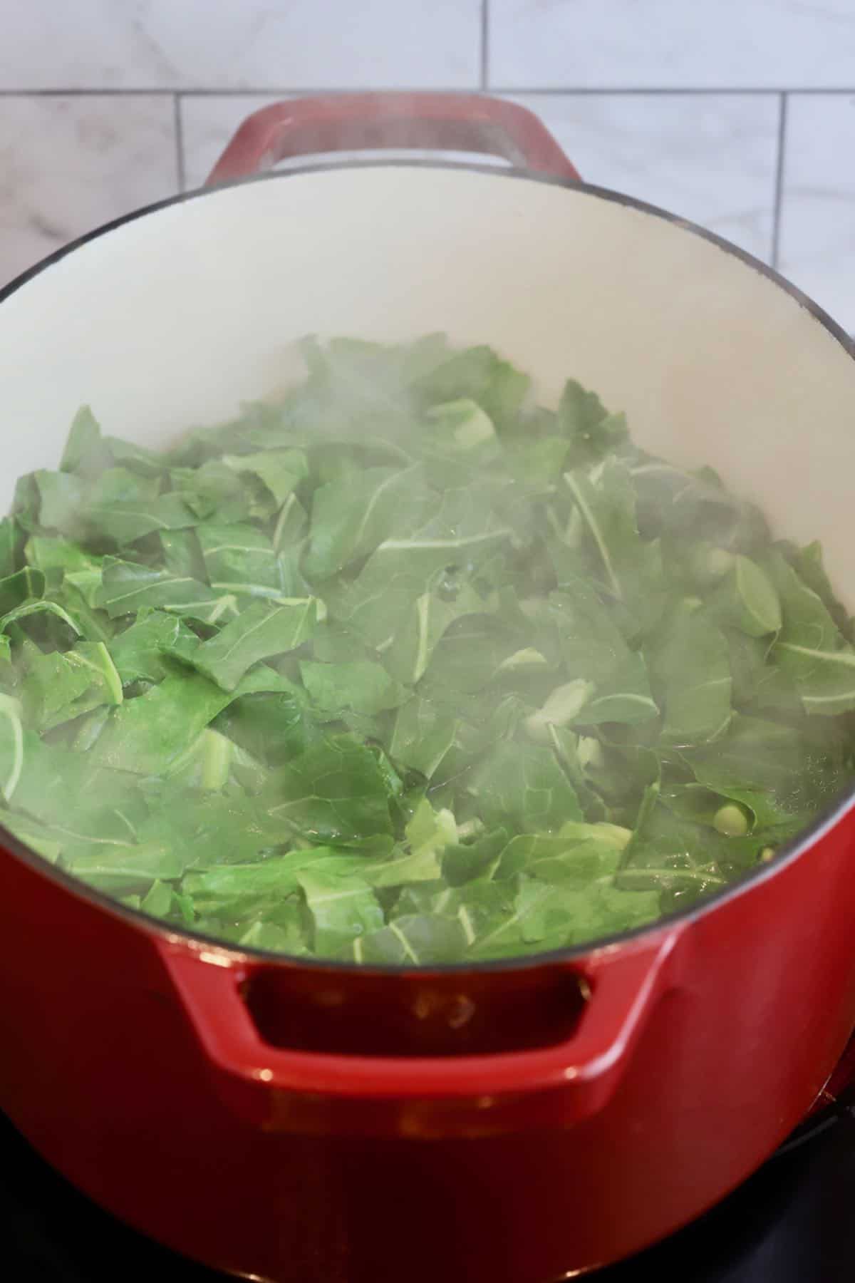 Collard greens cooking in a large Dutch oven. 