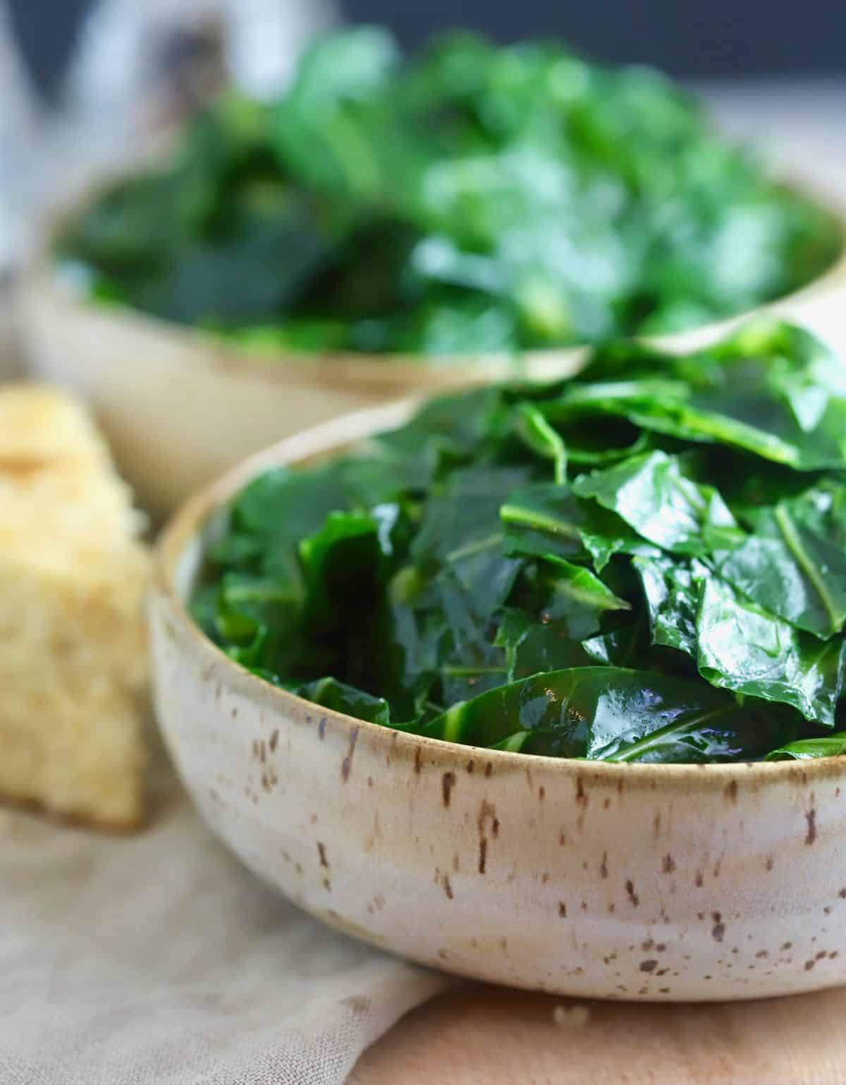 A brown bowl full of cooked collard greens. 