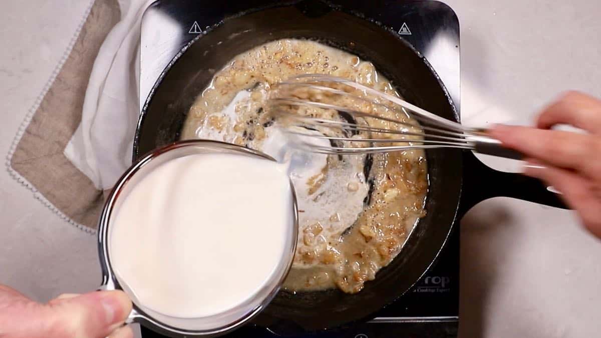 Making a sauce in a skillet by adding cream to cooked flour. 