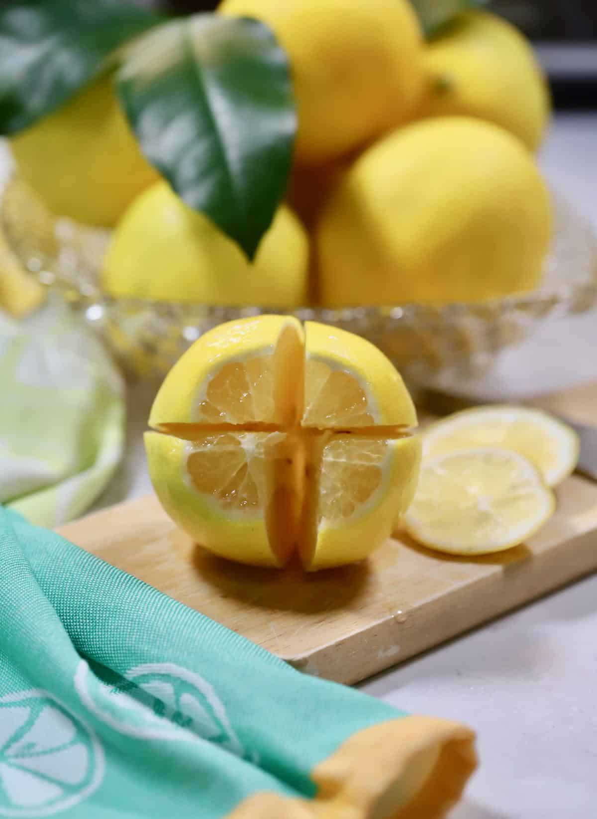 A lemon cut into quarters on a cutting board. 