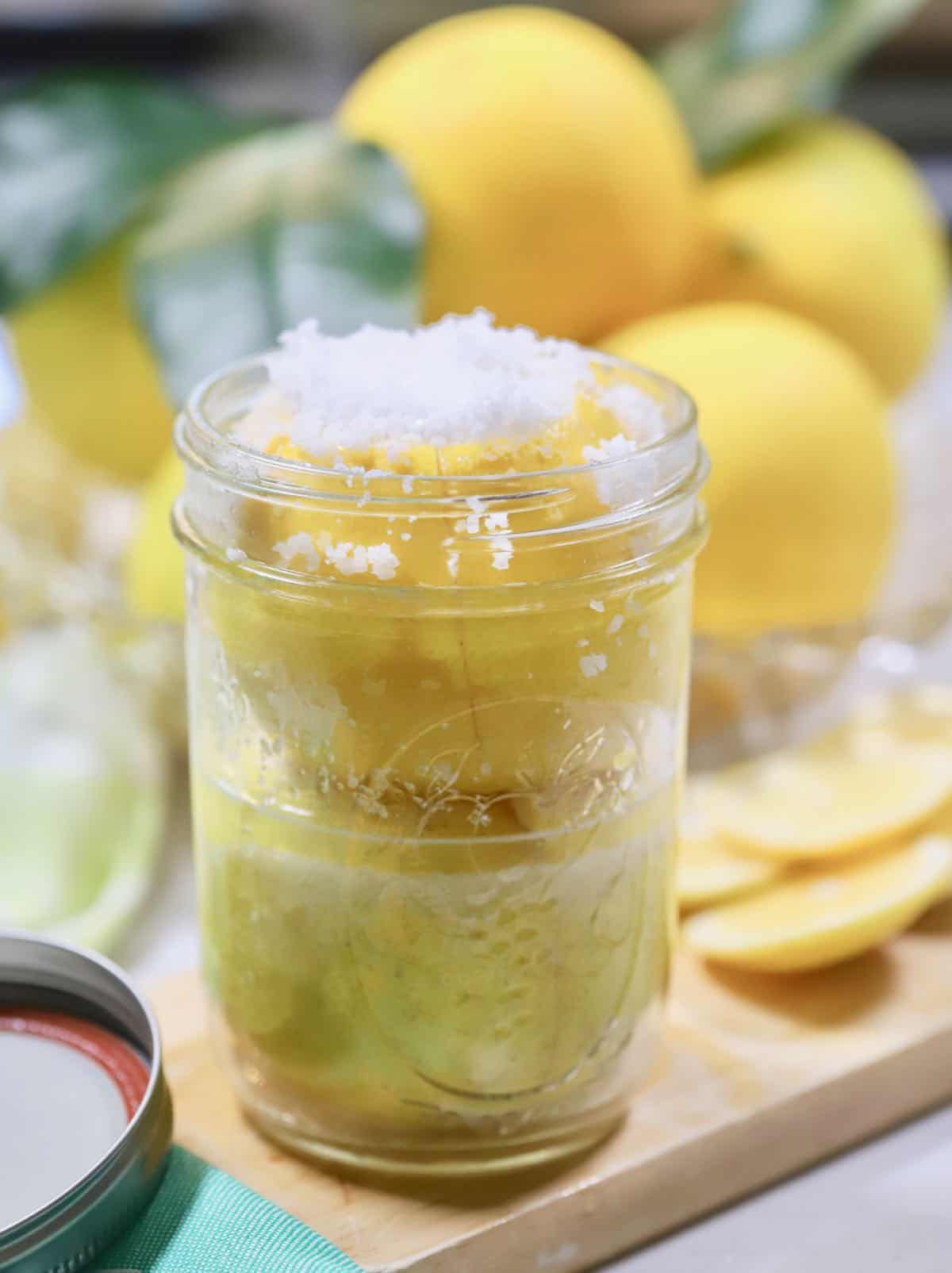 A mason jar with two lemons that are topped with salt. 