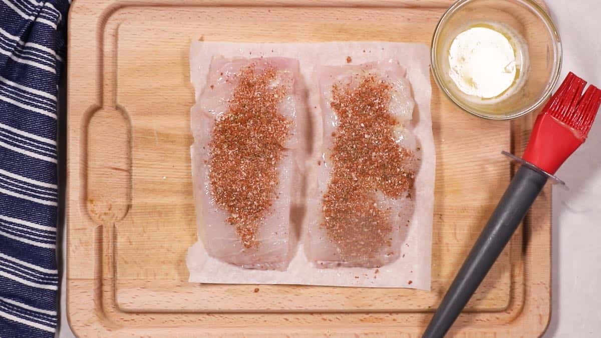 Two fish fillets topped with blackening seasoning.