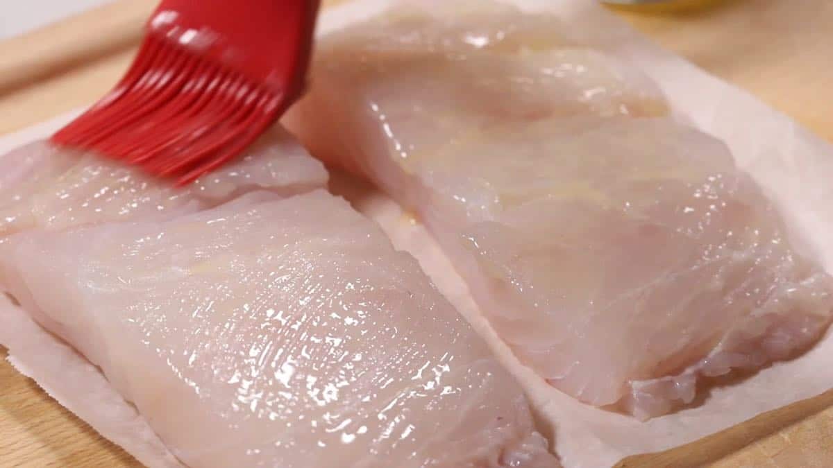 Using a pastry brush to coat fish fillets with butter. 