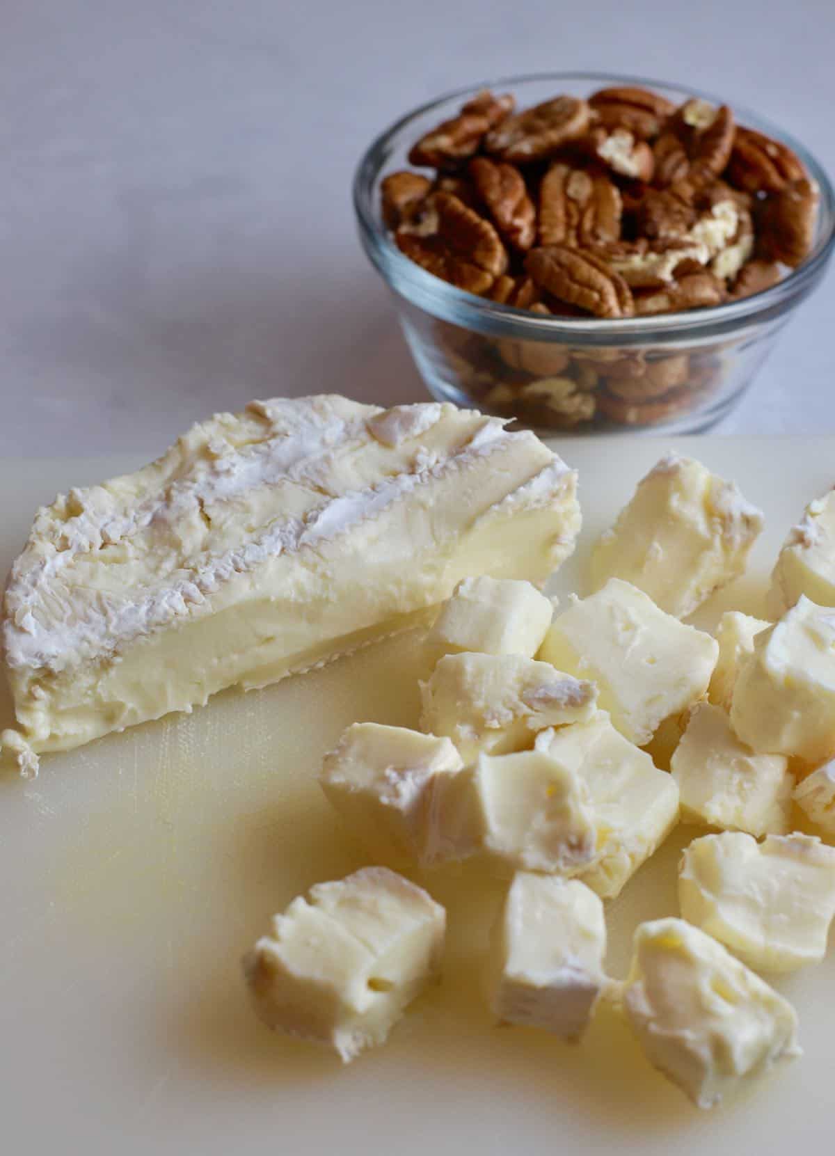 A wheel of brie cheese cut into cubes. 