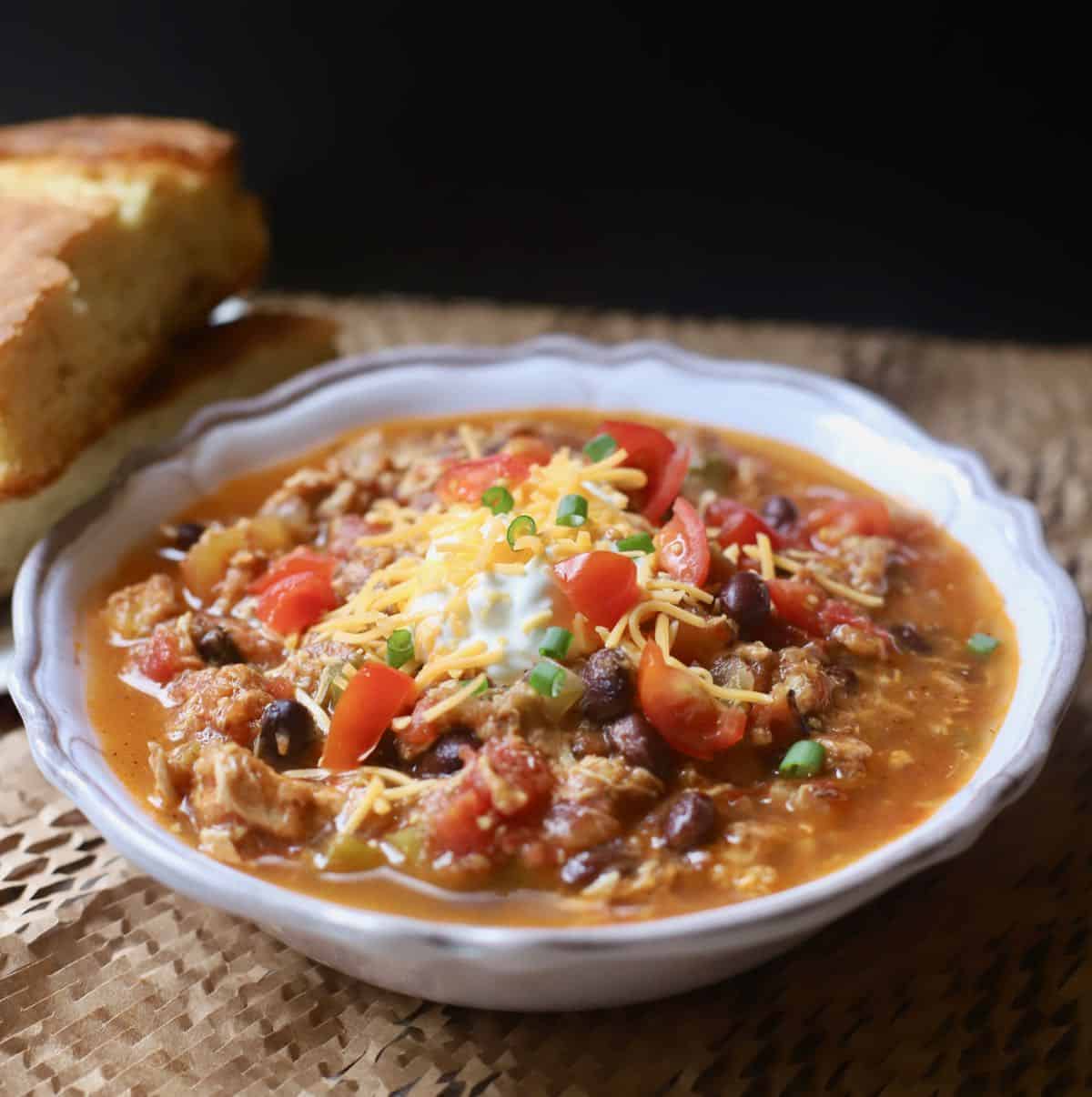 A bowl of Chicken Chili Verde and a slice of cornbread. 