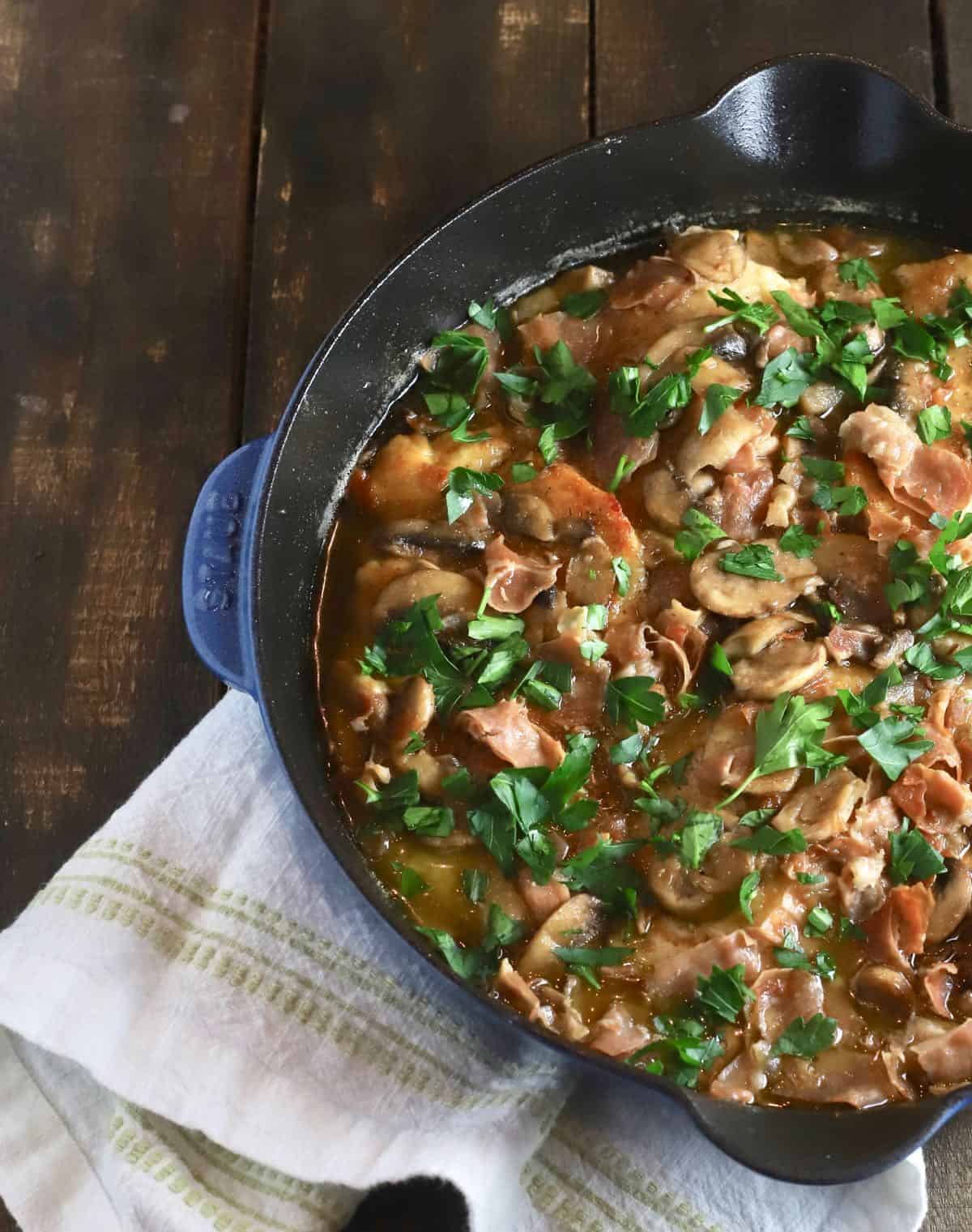 Chicken Marsala in a skillet topped with parsley. 