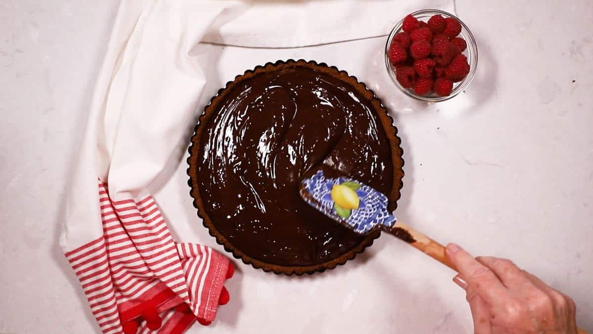 Using a rubber spatula to smooth our ganache filling in a tart crust.