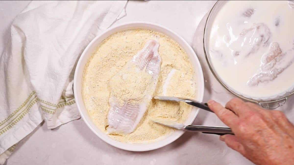 Dredging a fish fillet in a cornmeal mixture. 