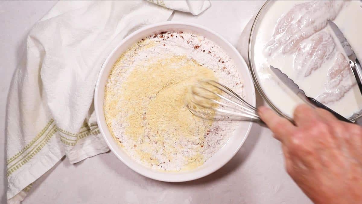 Using a whisk to mix cornmeal and seasonings. 