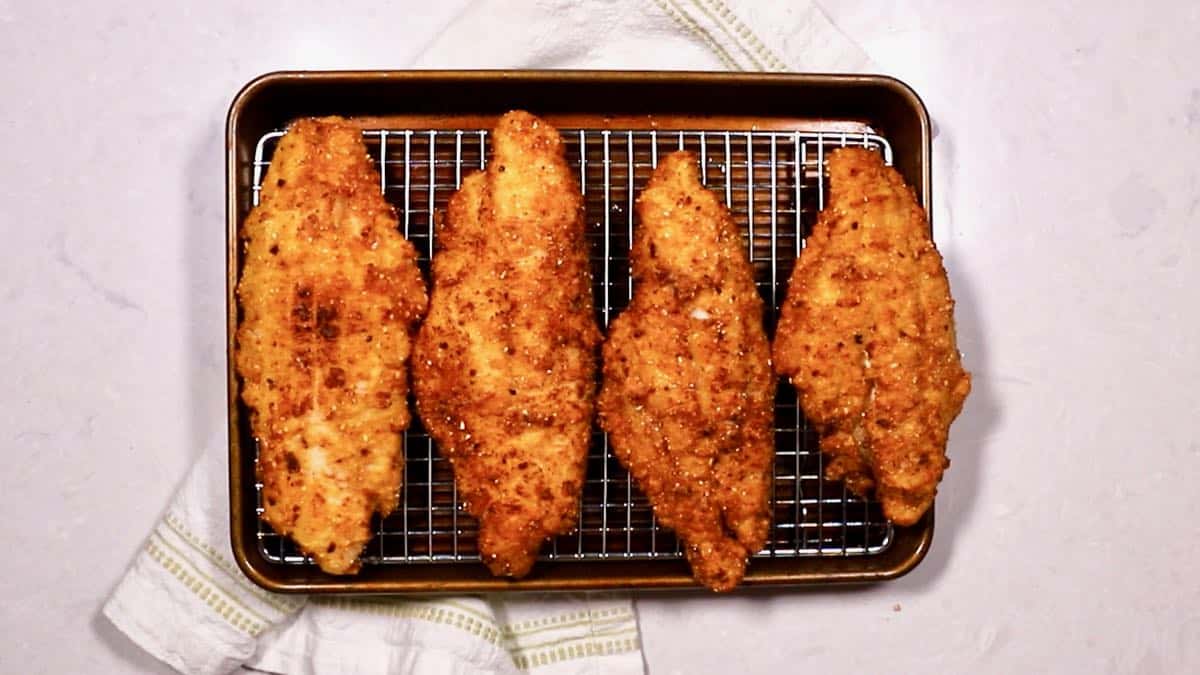 Fried catfish fillets draining on a wire rack. 