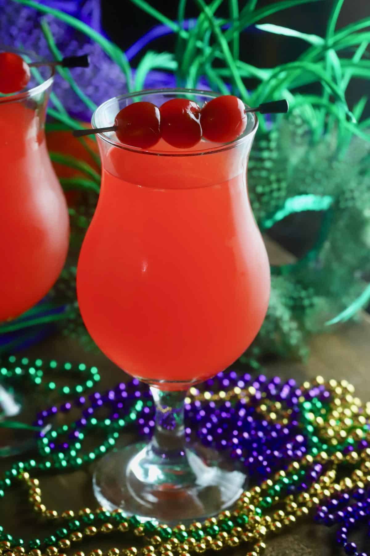 A hurricane cocktail garnished with cherries.