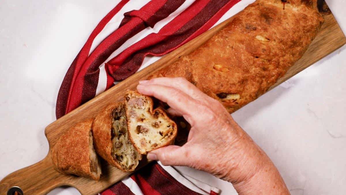 Holding a slice of sausage bread filled with pork sausage and mozzarella cheese.