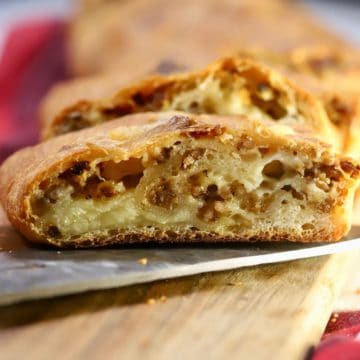 A slice of sausage bread on a cutting board.