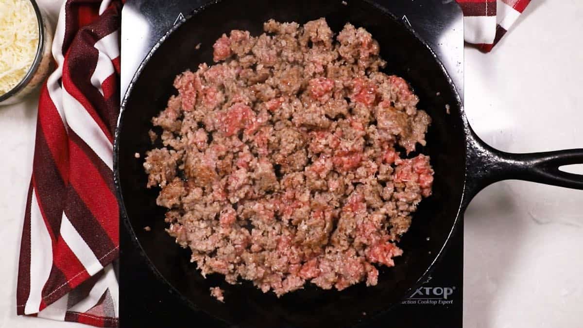 Sausage cooking in a cast-iron skillet. 