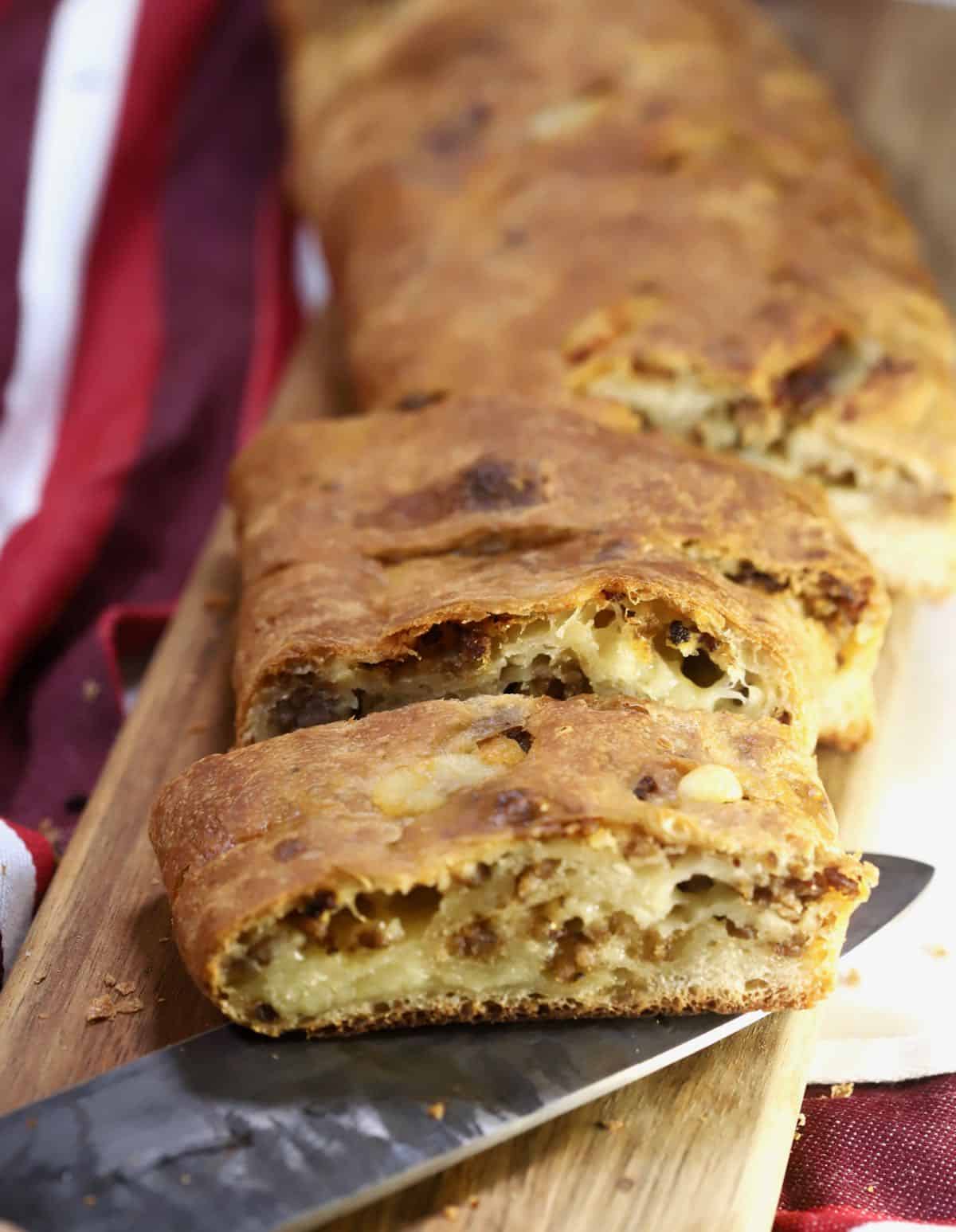 Sausage bread cut into slices on a cutting board. 