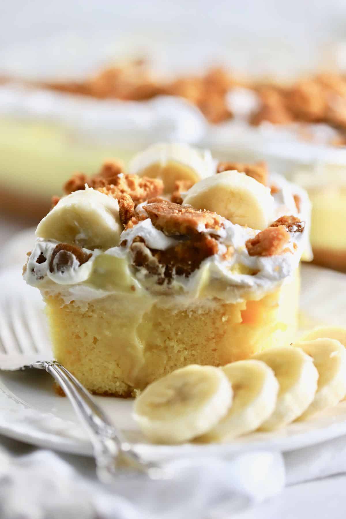 Banana Pudding Poke Cake on a plate with sliced bananas. 