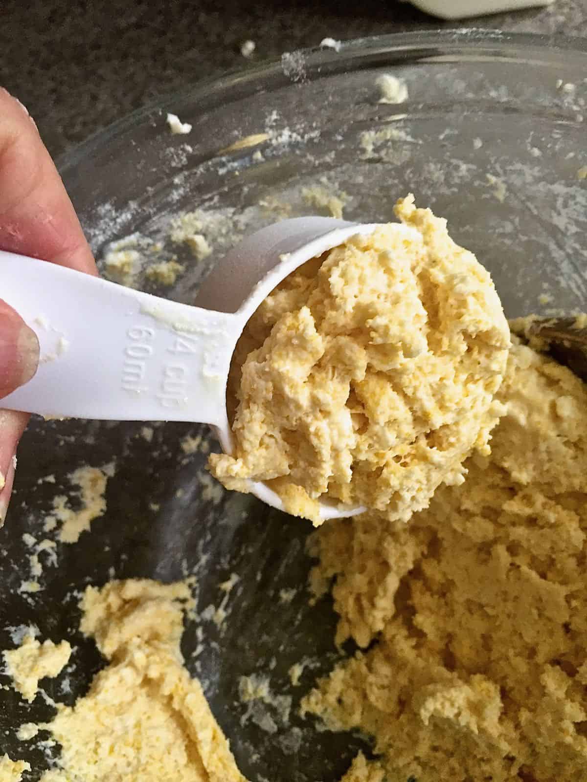 A measuring cup with biscuit dough to make drop biscuits.