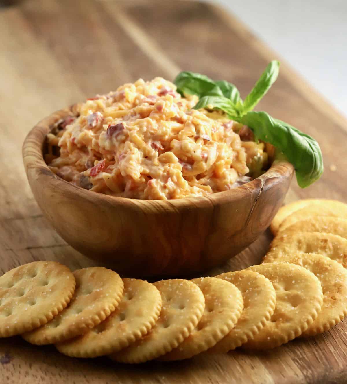 A wooden bowl full of pimento cheese spread. 