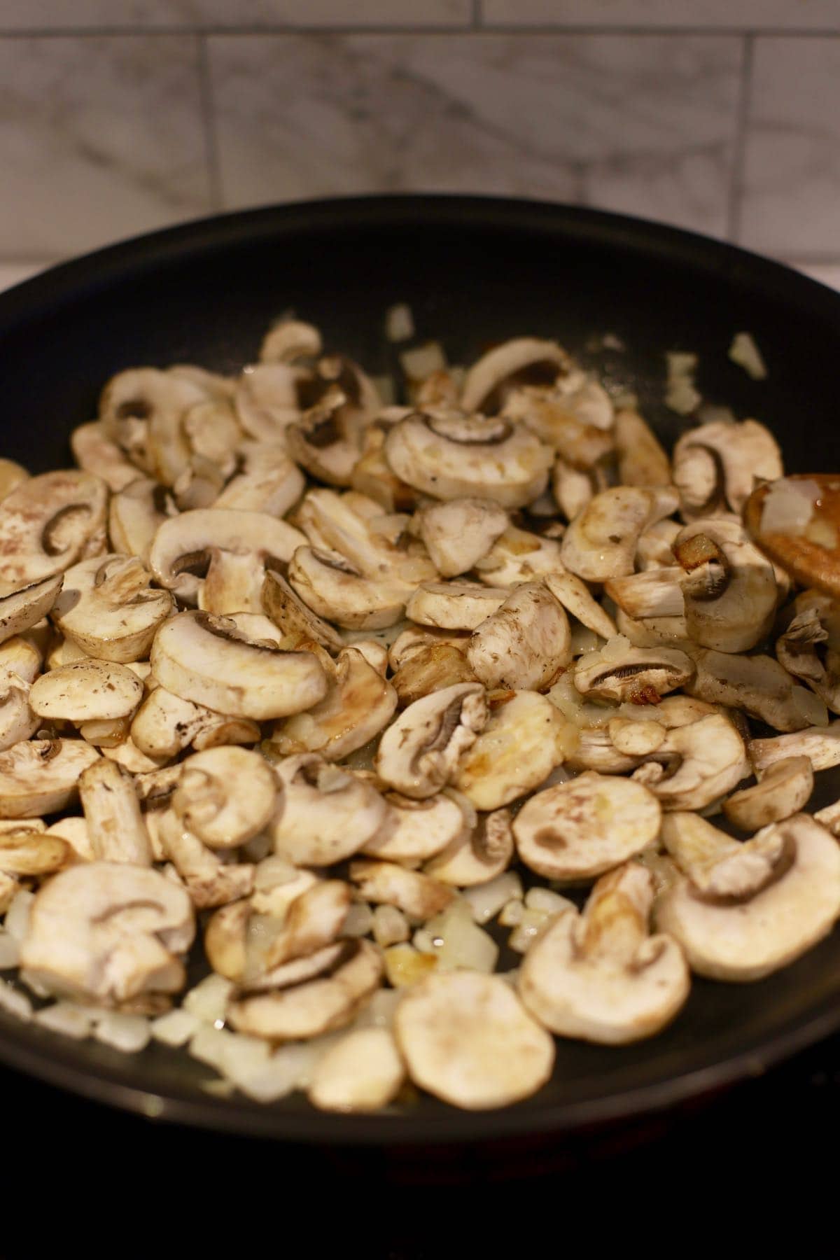 Cooking sliced mushrooms in a skillet.