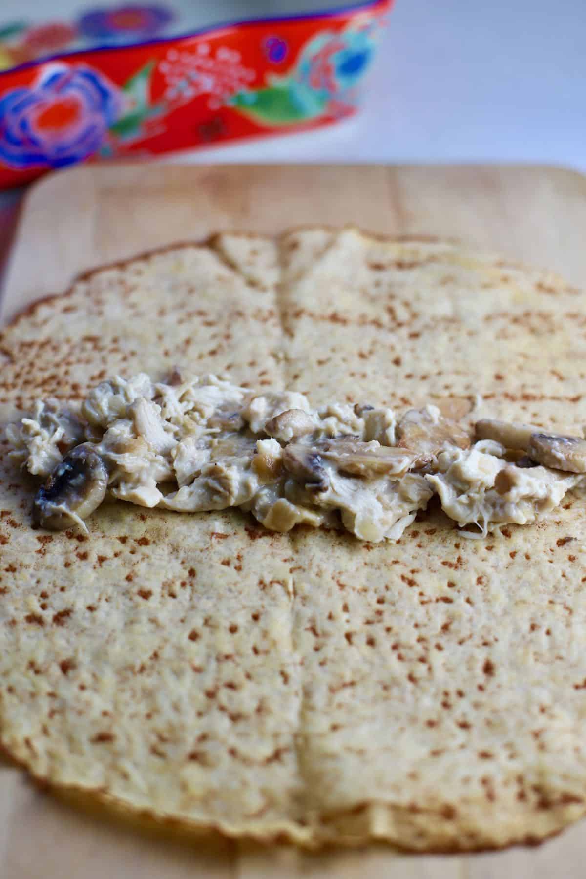 A crepe with chicken, mushrooms and mornay sauce in the middle.