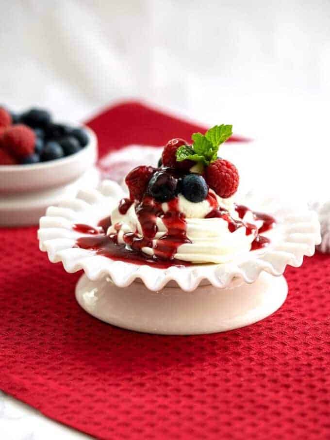 Meringue Chantilly on a white serving dish topped with raspberry sauce. 
