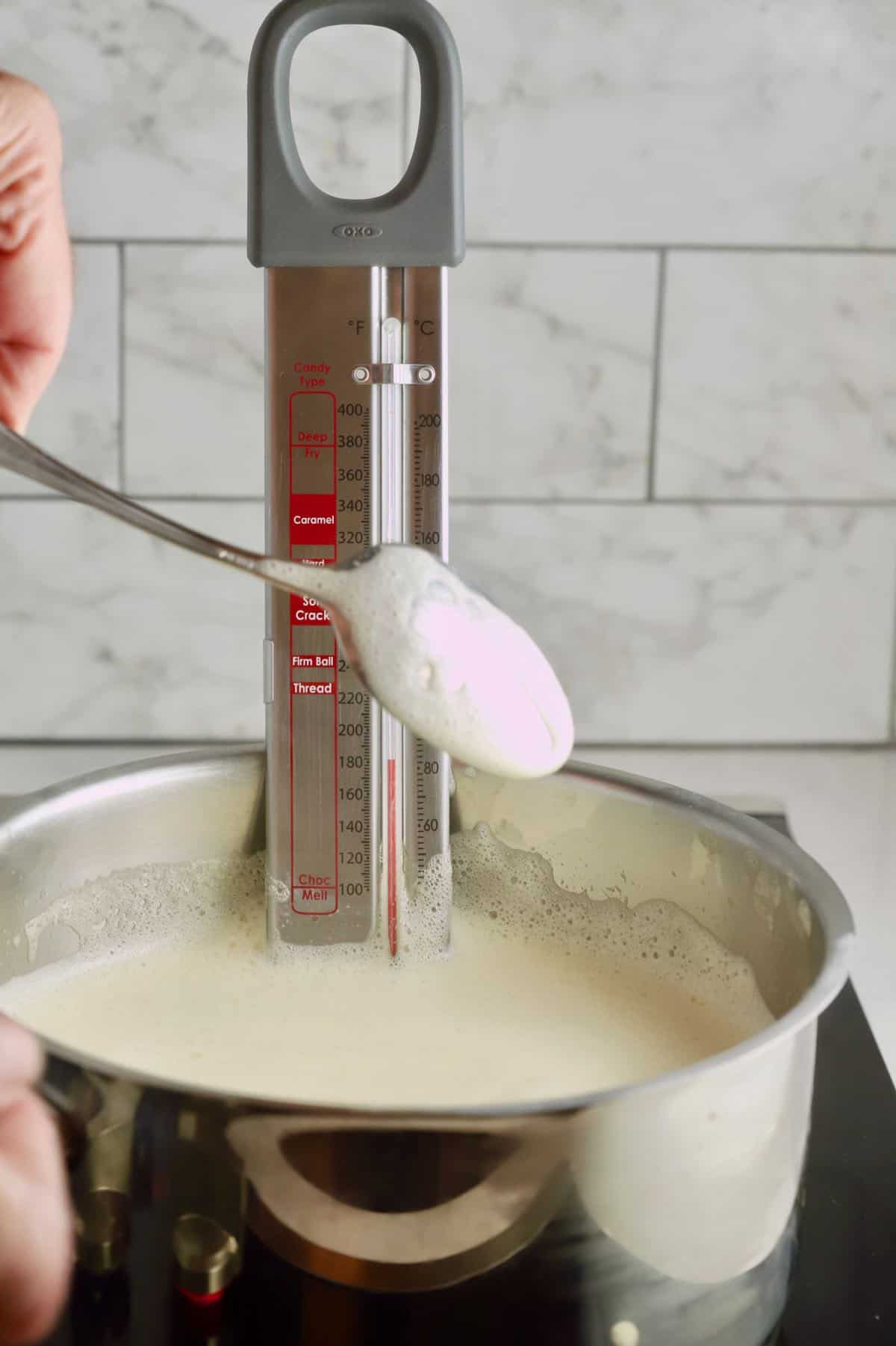 Cooking ice cream custard in a saucepan with a candy thermometer.