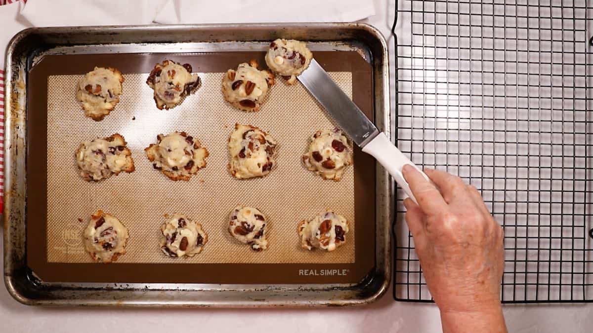 Using a spatula to remove cooled cookies from a baking sheet.