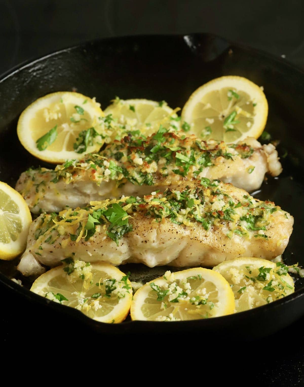 Two grouper fillets in a cast-iron skillet topped with gremolata. 