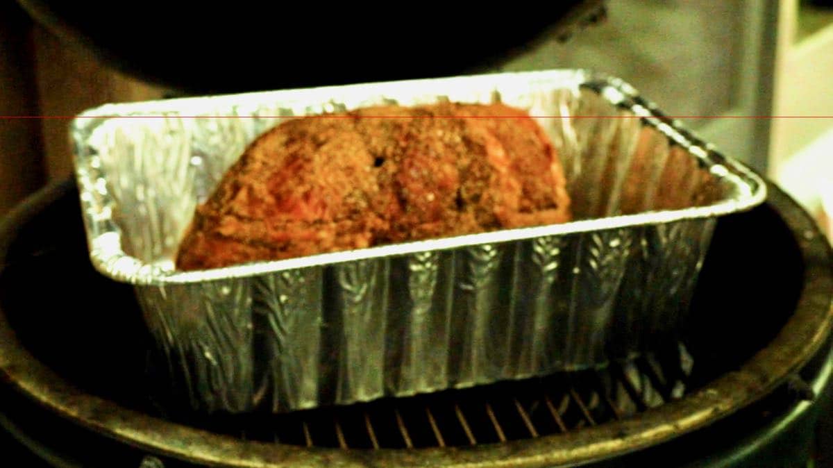 Ham in an aluminum pan on a grill. 