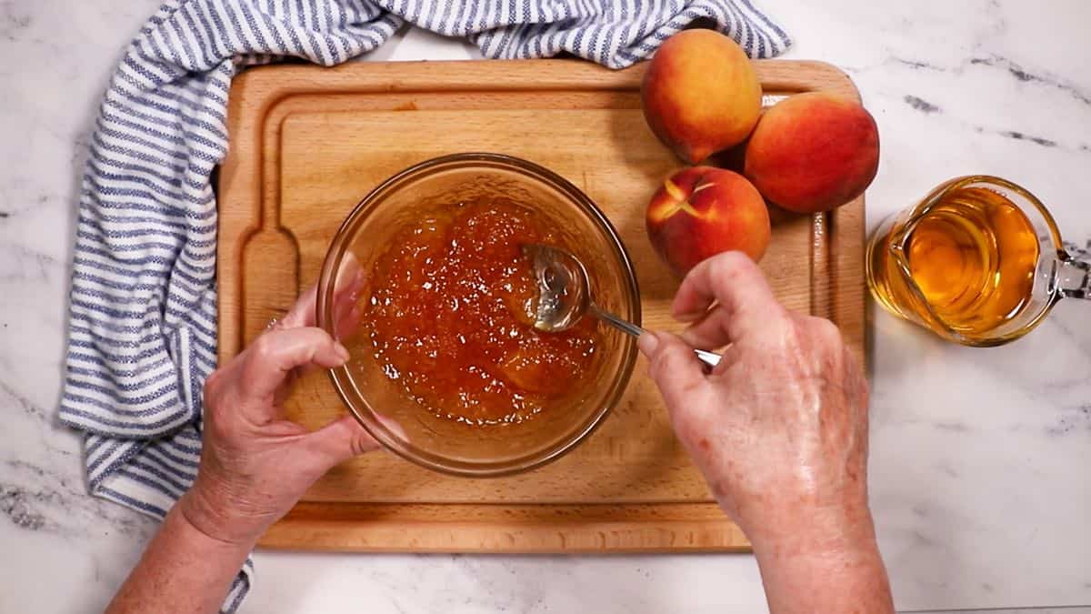 Stirring peach glaze in a bowl.