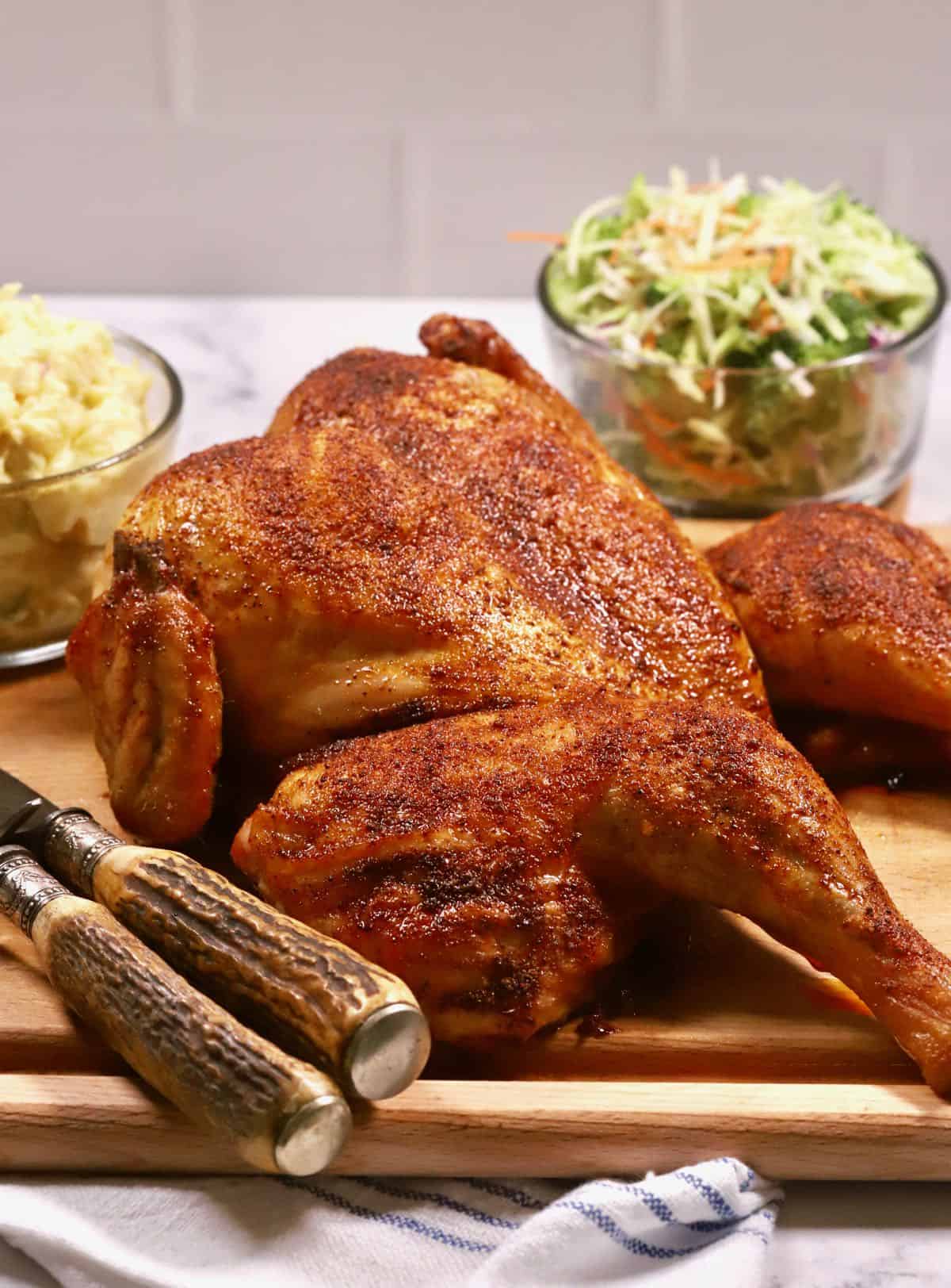 A whole smoked spatchcock chicken on a cutting board.