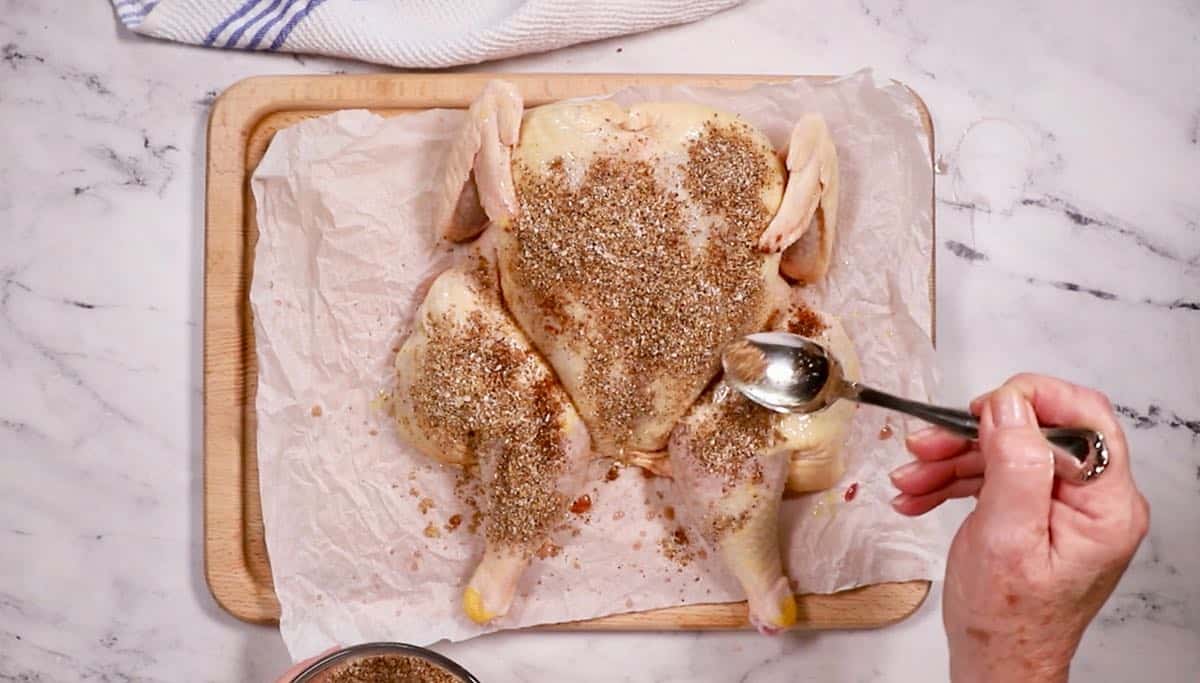 Topping a spatchcocked chicken with a dry rub.