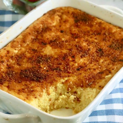 An oven-baked Cheese Grits Casserole in a white baking dish.
