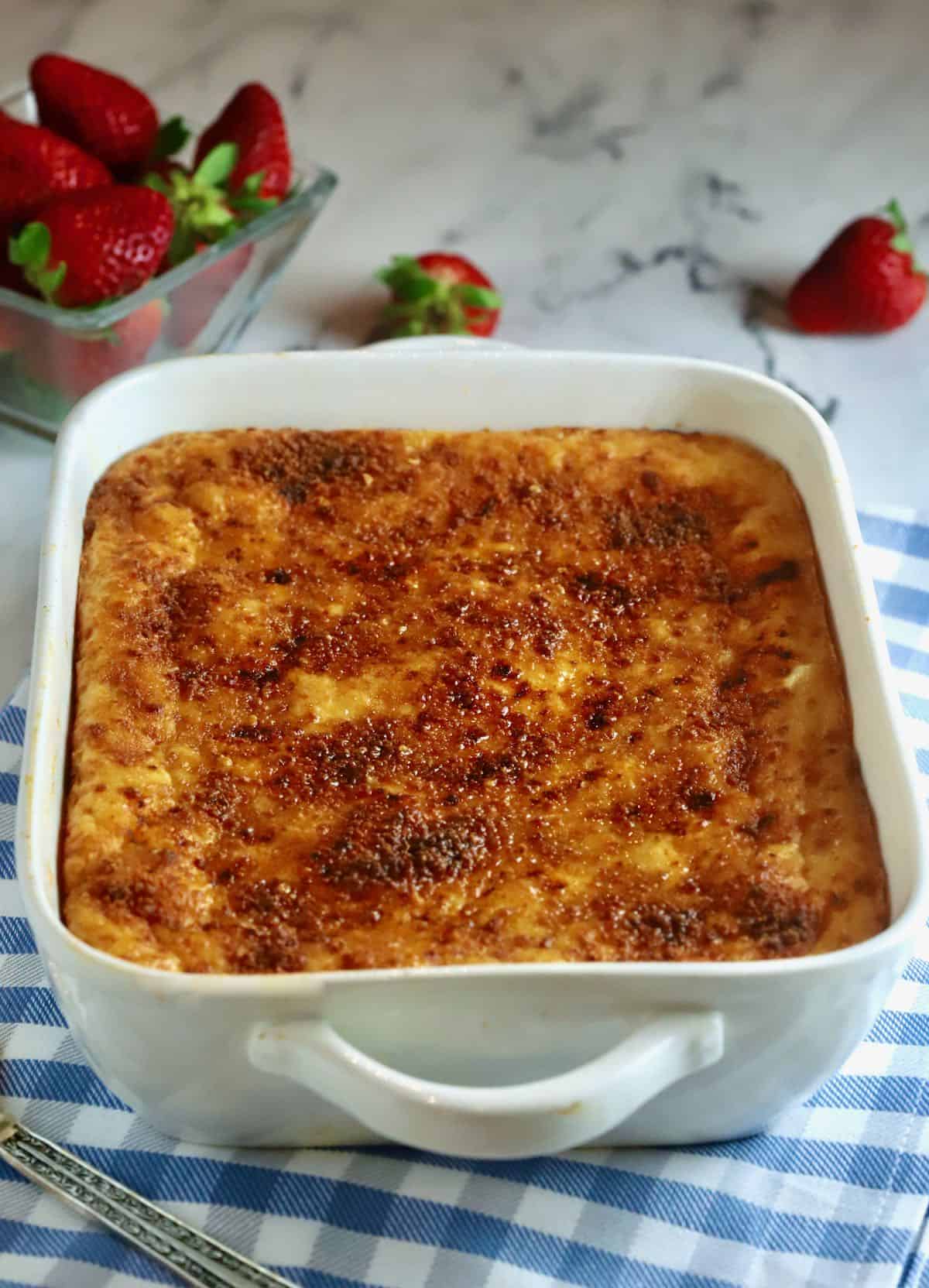 A baked cheese grits casserole on a blue and white kitchen towel. 