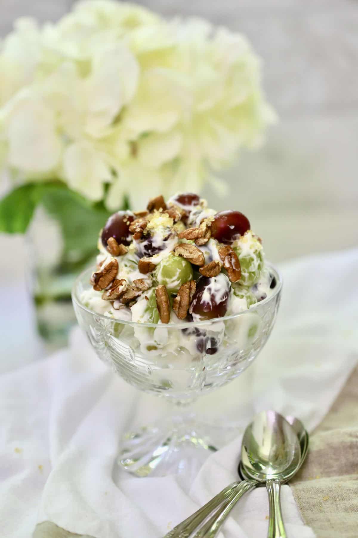 Grape salad topped with pecans in a crystal dessert dish. 