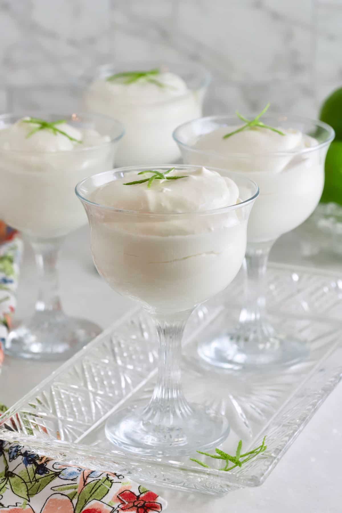 Key Lime Mouse in dessert glassed topped with strips of lime peel. 