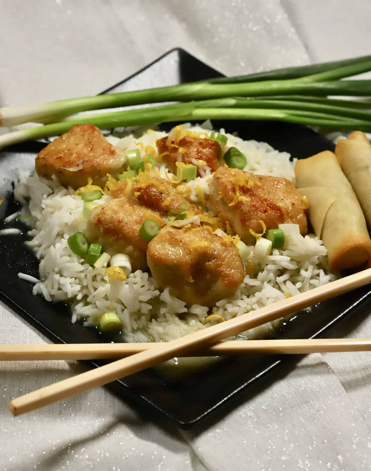 Pan-seared chicken pieces served over rice with scallions on top. 