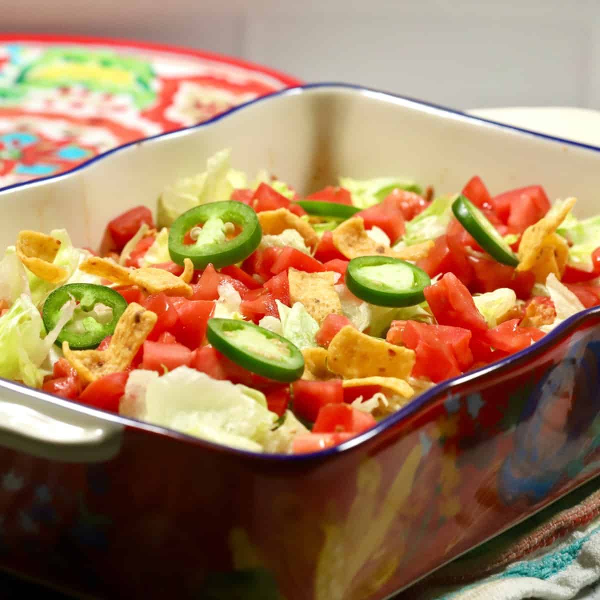 Walking Taco Casserole in a brightly colored baking dish, topped with lettuce and tomatoes.
