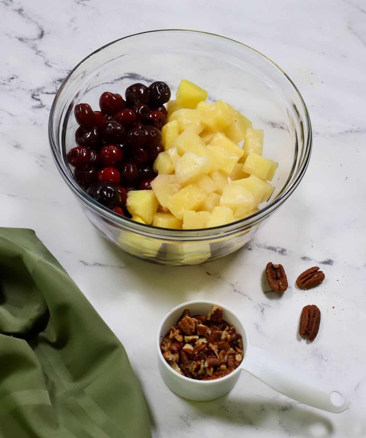 Cherries and pineapple chunks in a glass bowl.
