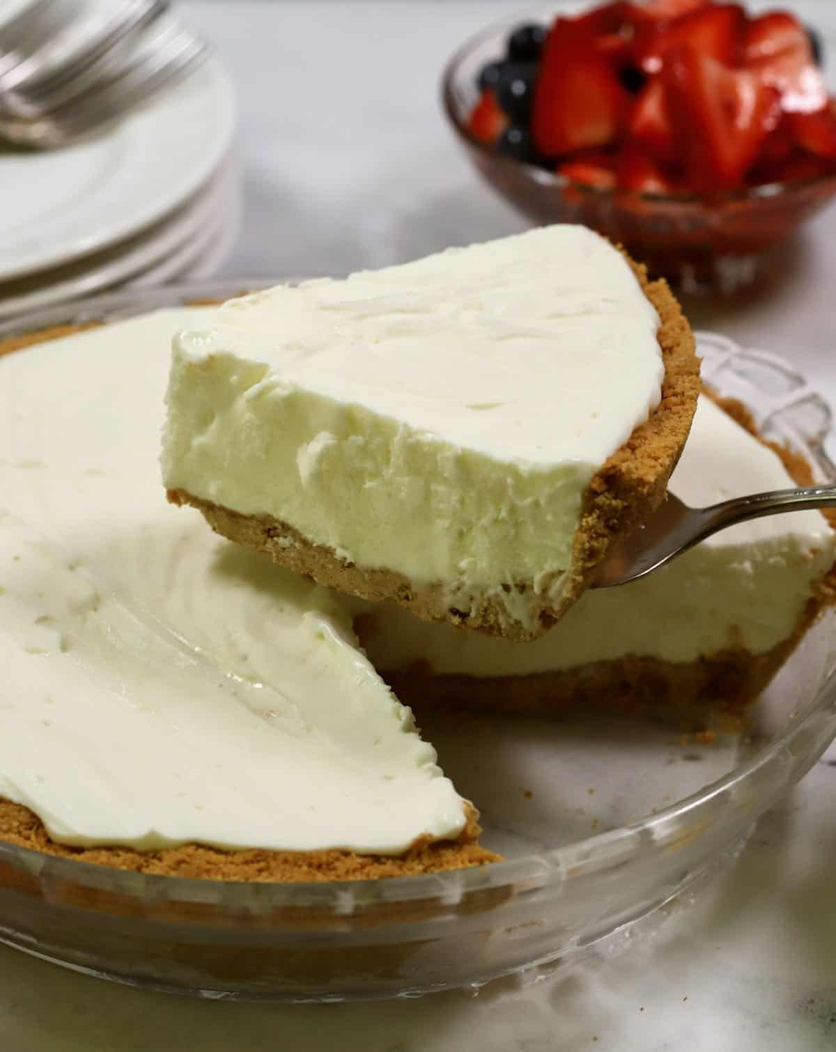 A frozen lemonade pie with a slice cut out on a pie server. 