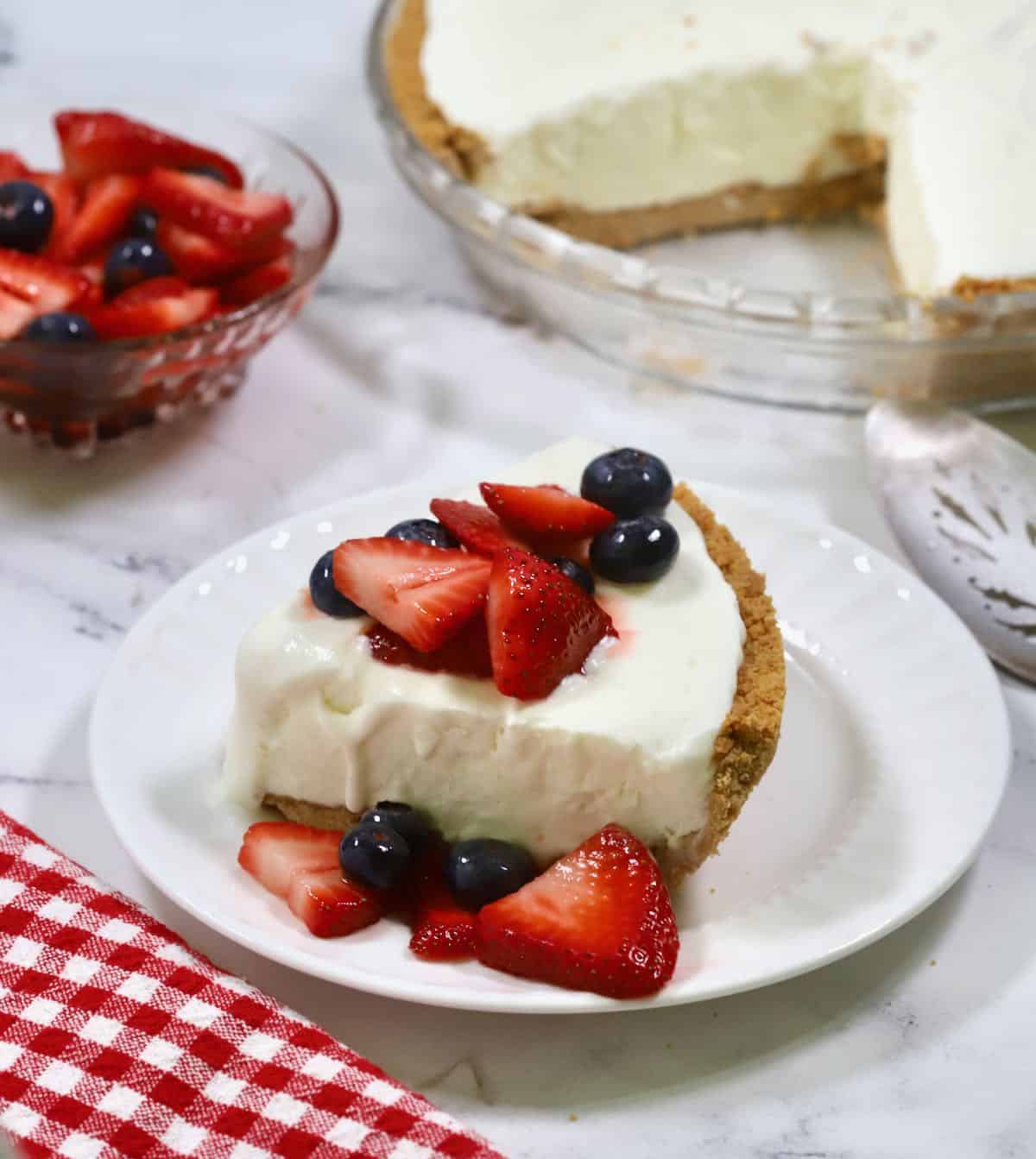 A slice of frozen lemonade pie topped with macerated berries. 