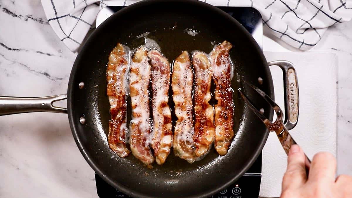 Pan-frying bacon in a skillet.