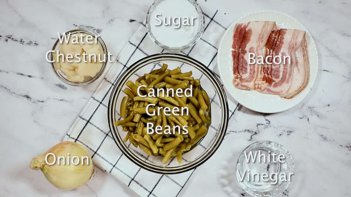 A bowl of canned green beans, bacon, onion and other ingredients for sweet and sour green beans. 